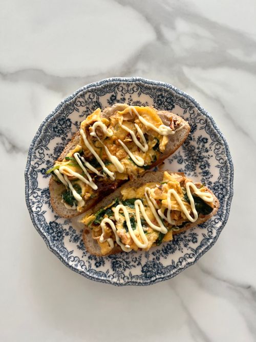 Free Delicious open-faced sandwich with eggs and spinach on a decorative plate. Perfect breakfast idea. Stock Photo
