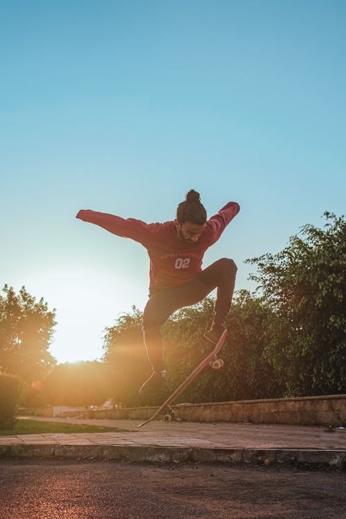 Free A skateboarder performs an aerial trick in a skate park during sunset, showcasing dynamic movement and skill. Stock Photo