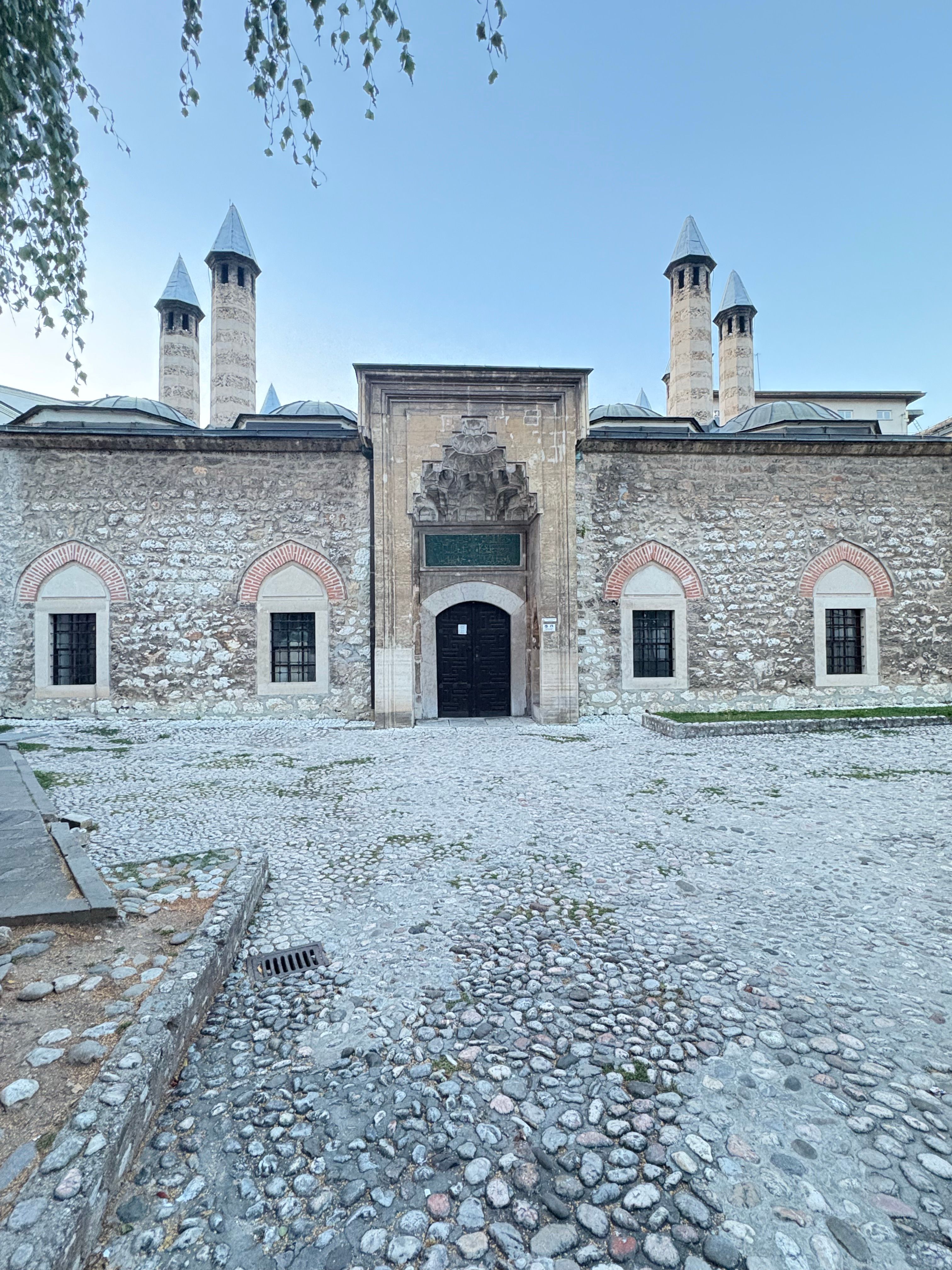 Majestic Ottoman building featuring conical towers and stone facade on a cobblestone courtyard.