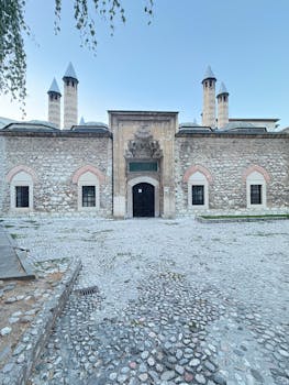Majestic Ottoman building featuring conical towers and stone facade on a cobblestone courtyard.