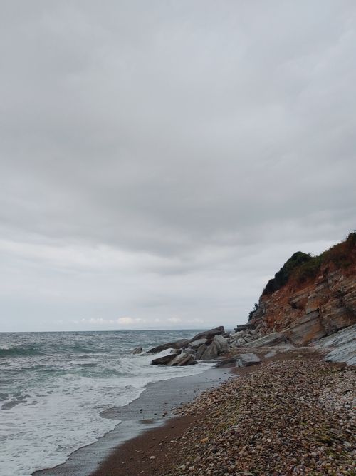 Free Serene view of a pebble-strewn beach with dramatic cliffs in Düzce, Türkiye, under a cloudy sky. Stock Photo