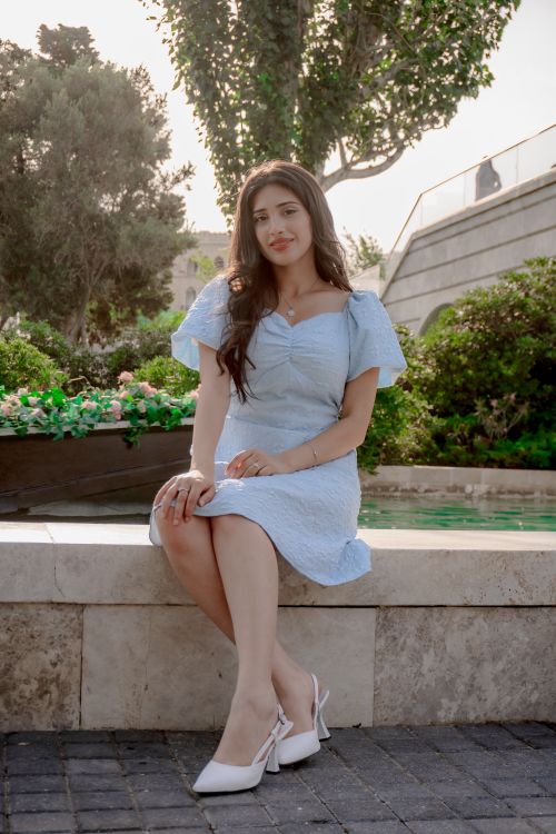 Free Stylish young woman in light blue dress poses gracefully by garden in Baku. Stock Photo