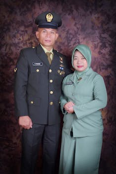 A portrait of a military couple in formal uniforms against a textured backdrop.