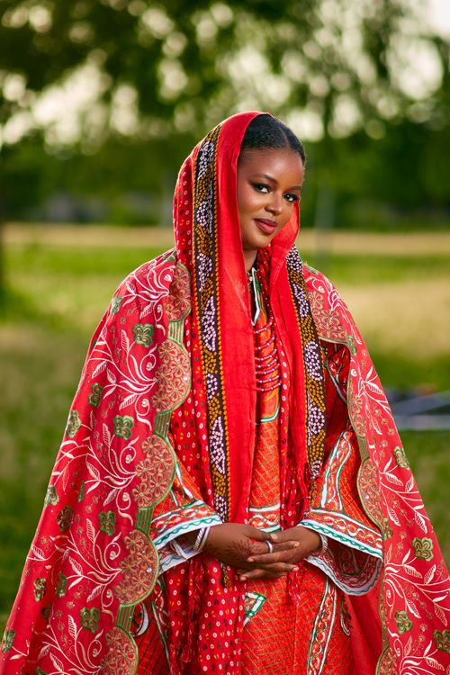Free Woman in vibrant traditional African attire standing outdoors, exuding elegance. Stock Photo