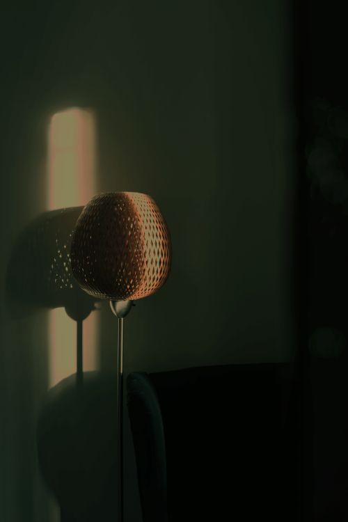 Free A solitary vintage lamp casting shadows in soft morning sunlight, creating a moody ambiance. Stock Photo