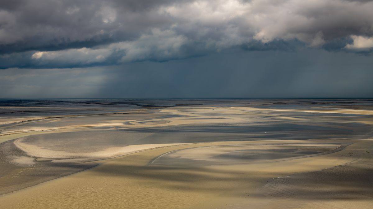 The wide golden tidal sands of the Baie de Somme under a vast sky