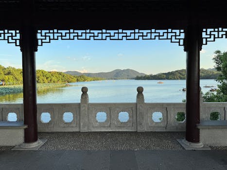 Serene view of West Lake framed by a traditional pavilion in Hangzhou, China.