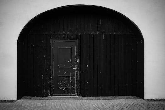 A vintage black wooden arched doorway in Romania, showcasing rustic architecture.
