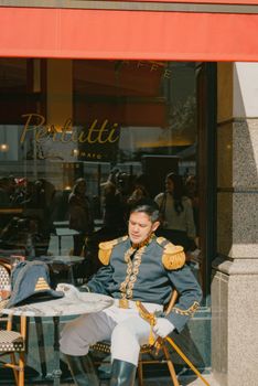 Man in historical military uniform sitting outside a cafe enjoying sunny day.