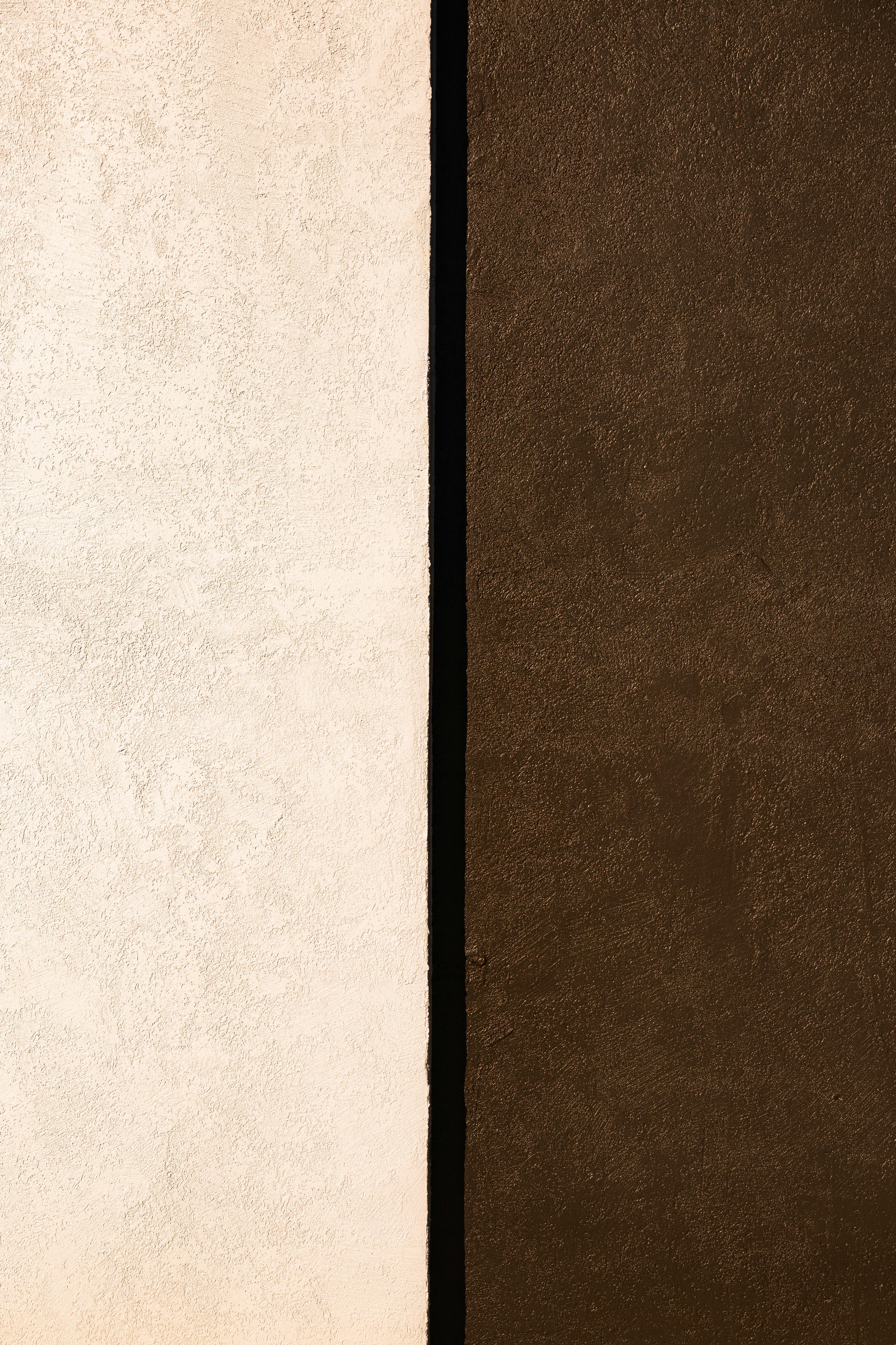 Vertical shot of a minimalist abstract texture with brown and white walls separated by a black line.