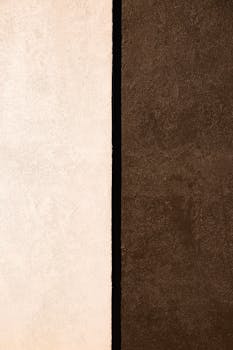Vertical shot of a minimalist abstract texture with brown and white walls separated by a black line.