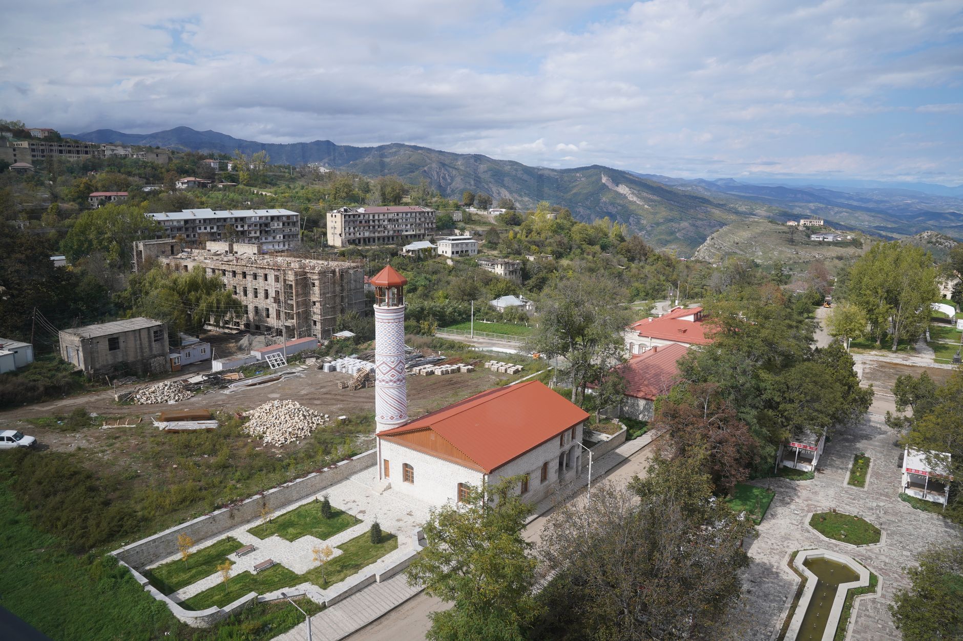 A scenic mountain village featuring a historic minaret under a blue sky.