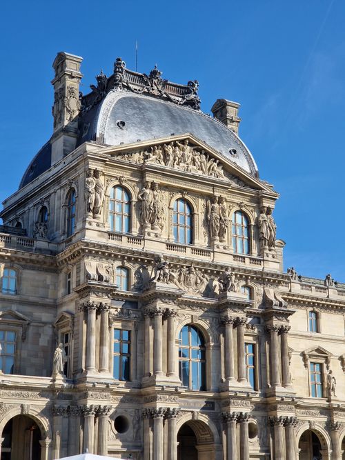 Free Stunning view of the architectural details on the Louvre Museum's facade in Paris under a clear blue sky. Stock Photo