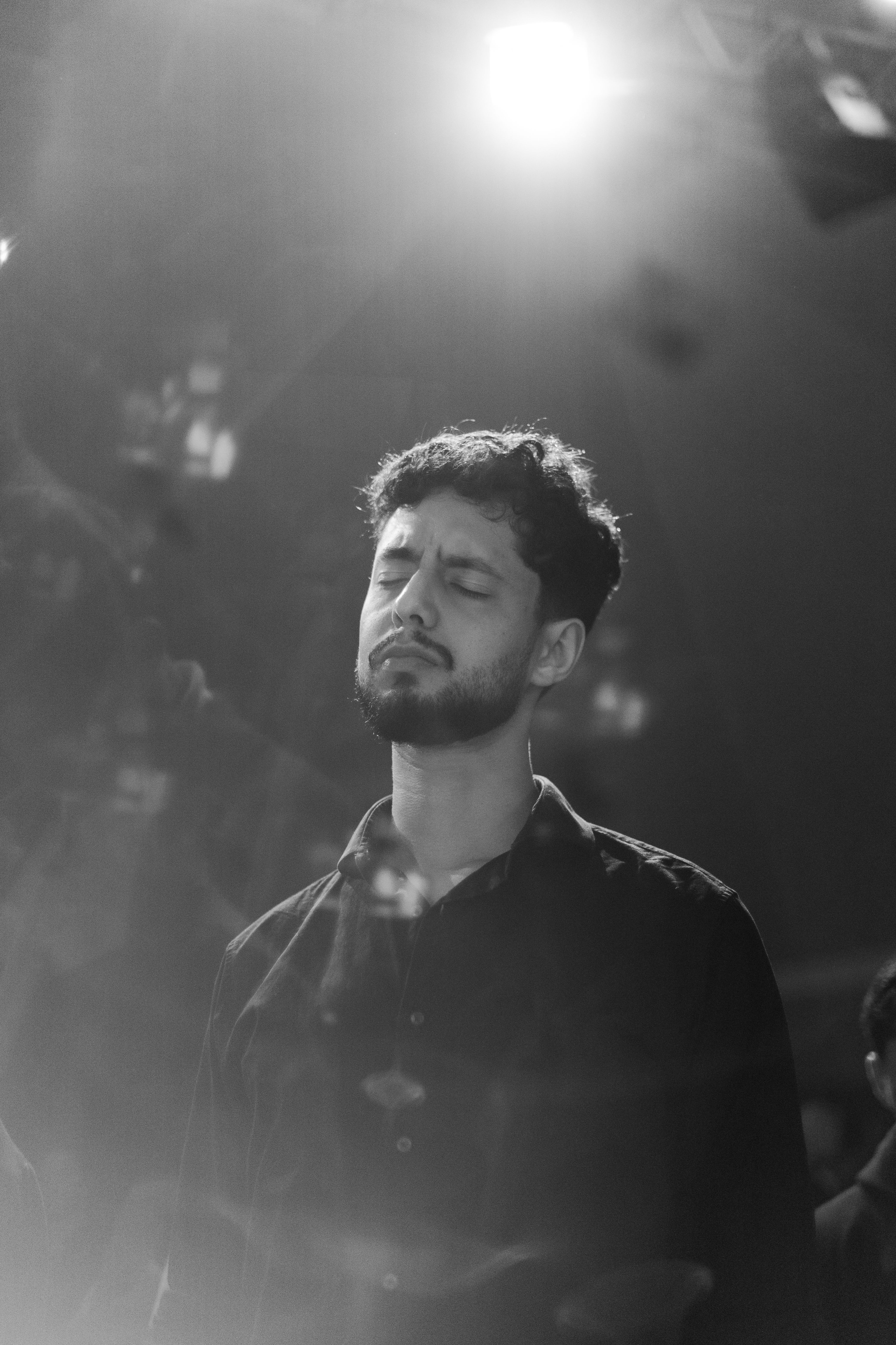 Expressive black and white portrait of a man lost in thought, captured indoors with dramatic lighting.