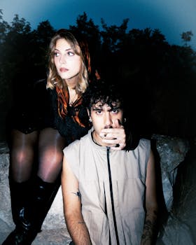 A cinematic nighttime portrait of two stylish individuals outdoors exuding alternative fashion vibes.