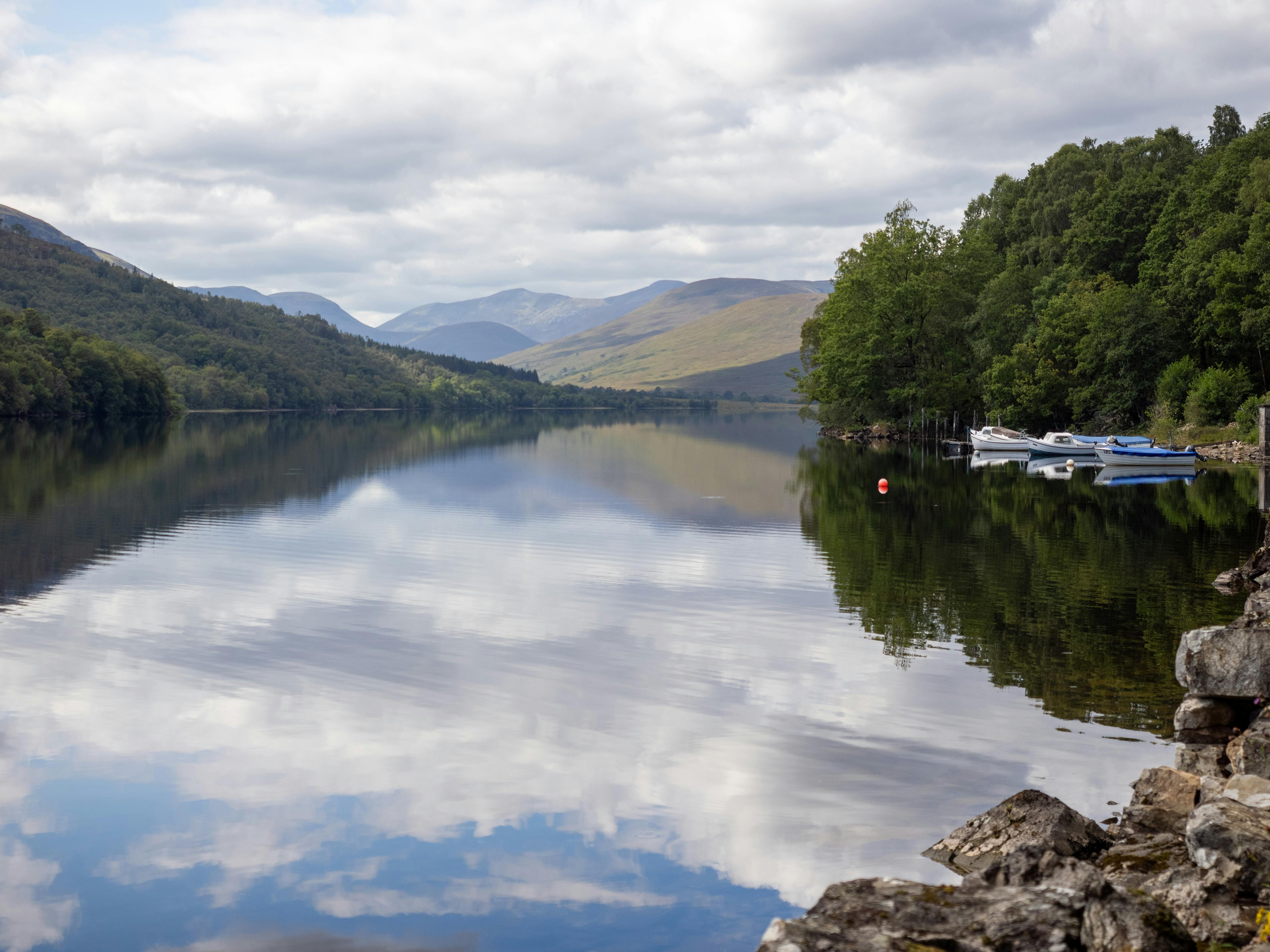 Serene landscape of a lake reflecting clouds and distant mountains, perfect for nature lovers.
