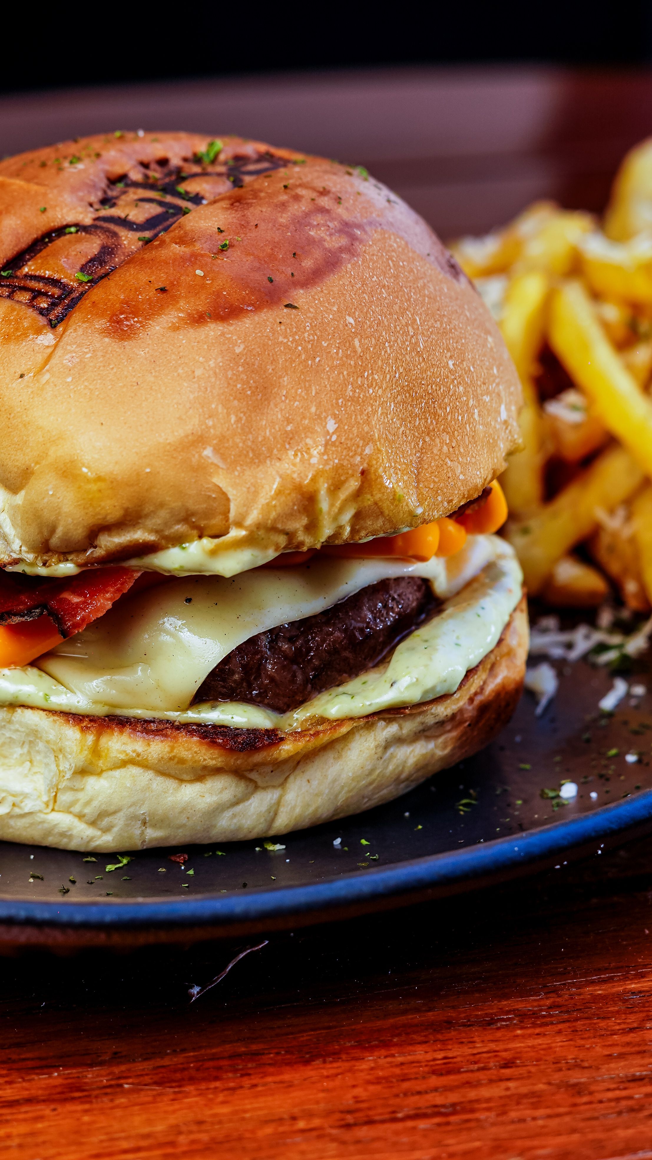 Tasty cheeseburger with juicy beef patty and fries served on a blue plate.