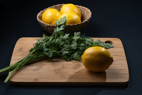 Free A vibrant still life of lemons and parsley on a wooden cutting board. Stock Photo