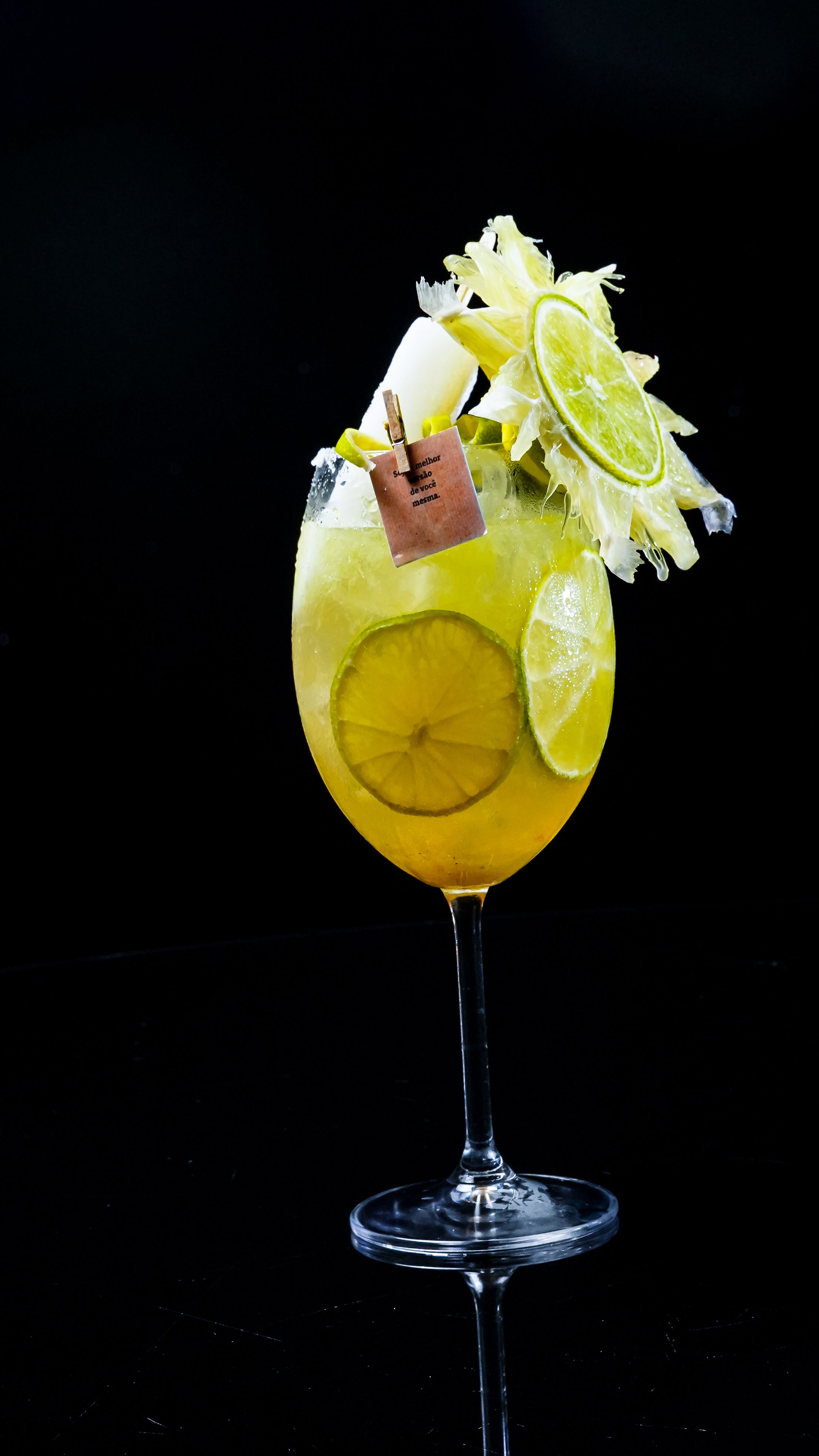 A refreshing cocktail in a wine glass, adorned with lime slices and a decorative tag, visually embodies the elegance and sophistication associated with glass dildos.
