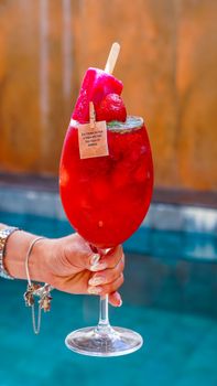 Vibrant red strawberry cocktail in a glass, perfect for summer refreshment by the pool.
