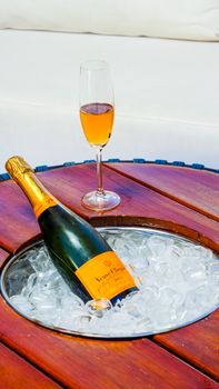 Image of a champagne bottle in an ice bucket with a filled flute on a wooden table, perfect for celebrations.