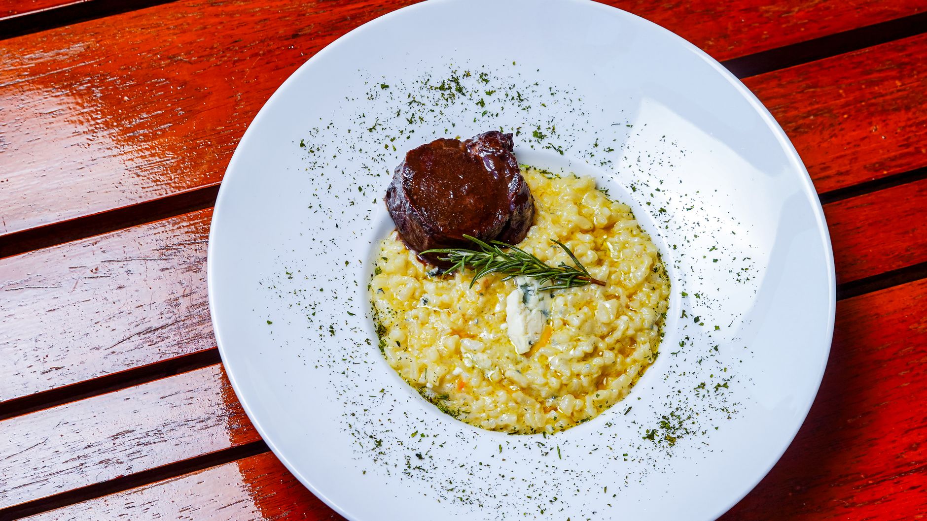 Bowl of barley risotto garnished with fresh herbs and lemon wedge