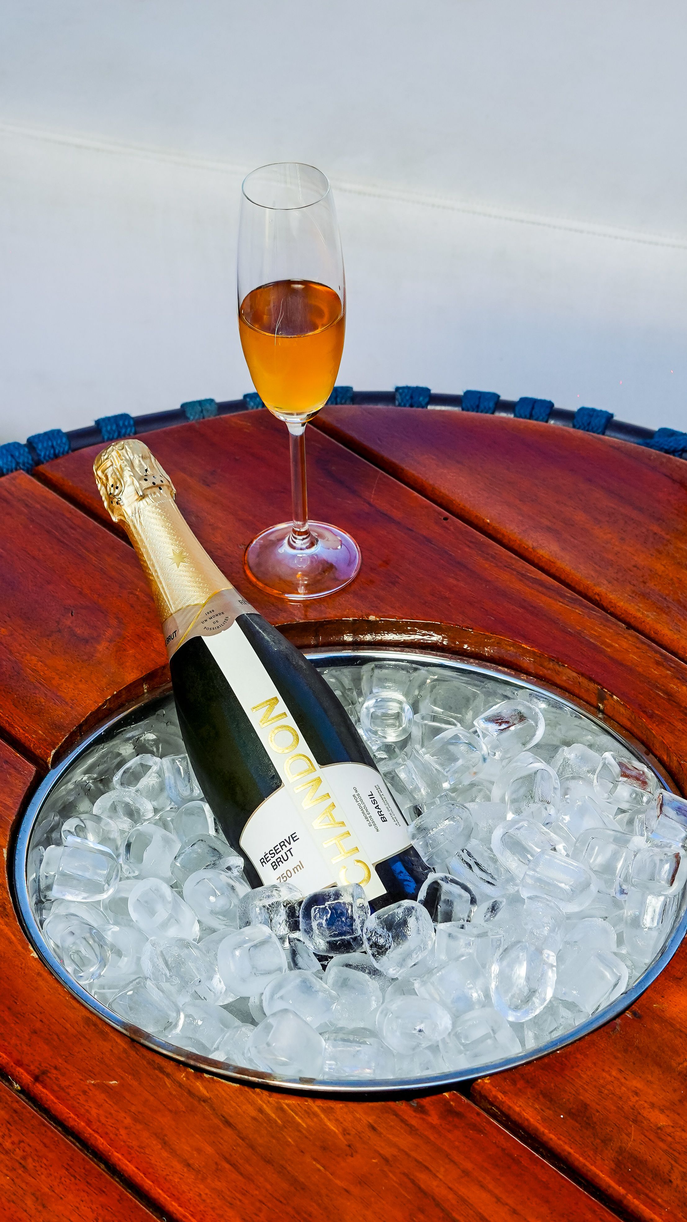 Elegant presentation of champagne bottle on ice with a glass on a wooden table.