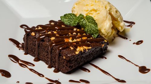 Free Rich chocolate brownie topped with nuts, served with a scoop of vanilla ice cream. Stock Photo