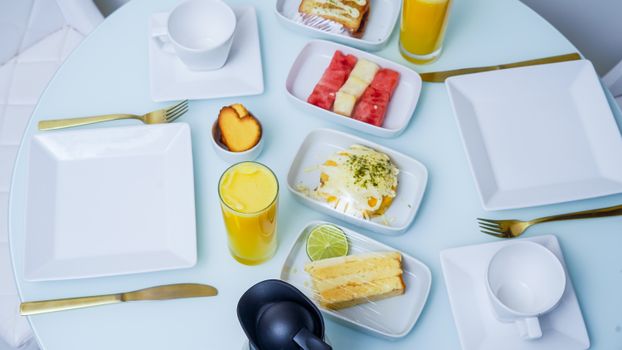 A beautifully arranged breakfast table featuring juices, fruits, and various dishes on white plates.