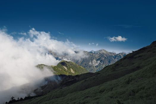 Majestic Hehuanshan mountain landscape in Taiwan with clouds drifting over green hills and peaks.