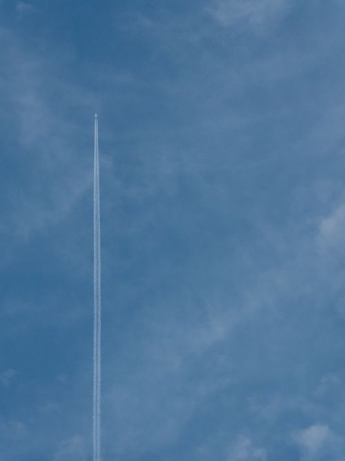 Free High-altitude airplane leaves a contrail in a bright blue sky, symbolizing travel and freedom. Stock Photo