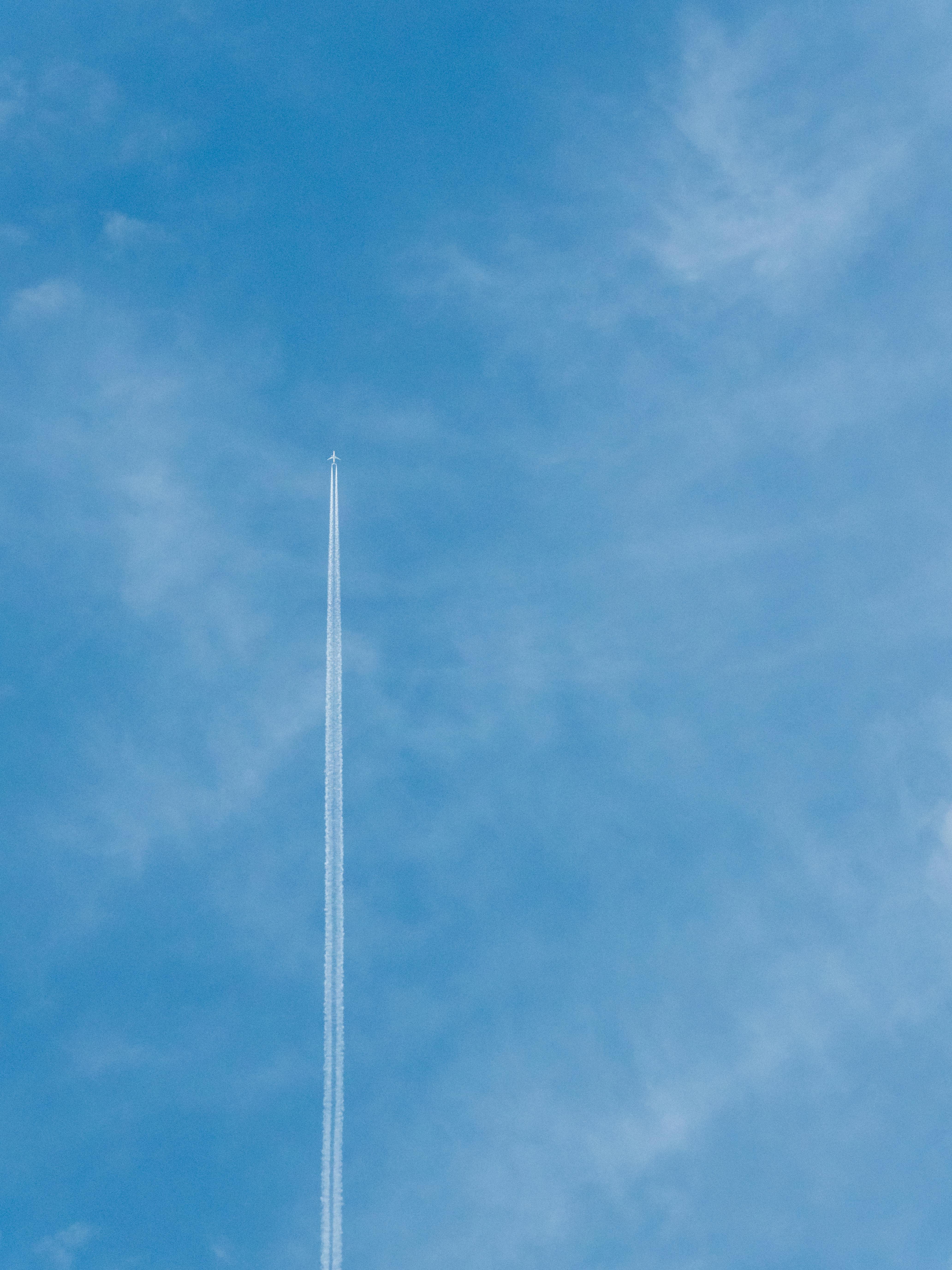 Gratuit Un avion volant à haute altitude laisse une traînée de condensation distincte sur un ciel bleu vif, capturant l'essence du voyage aérien. Photos