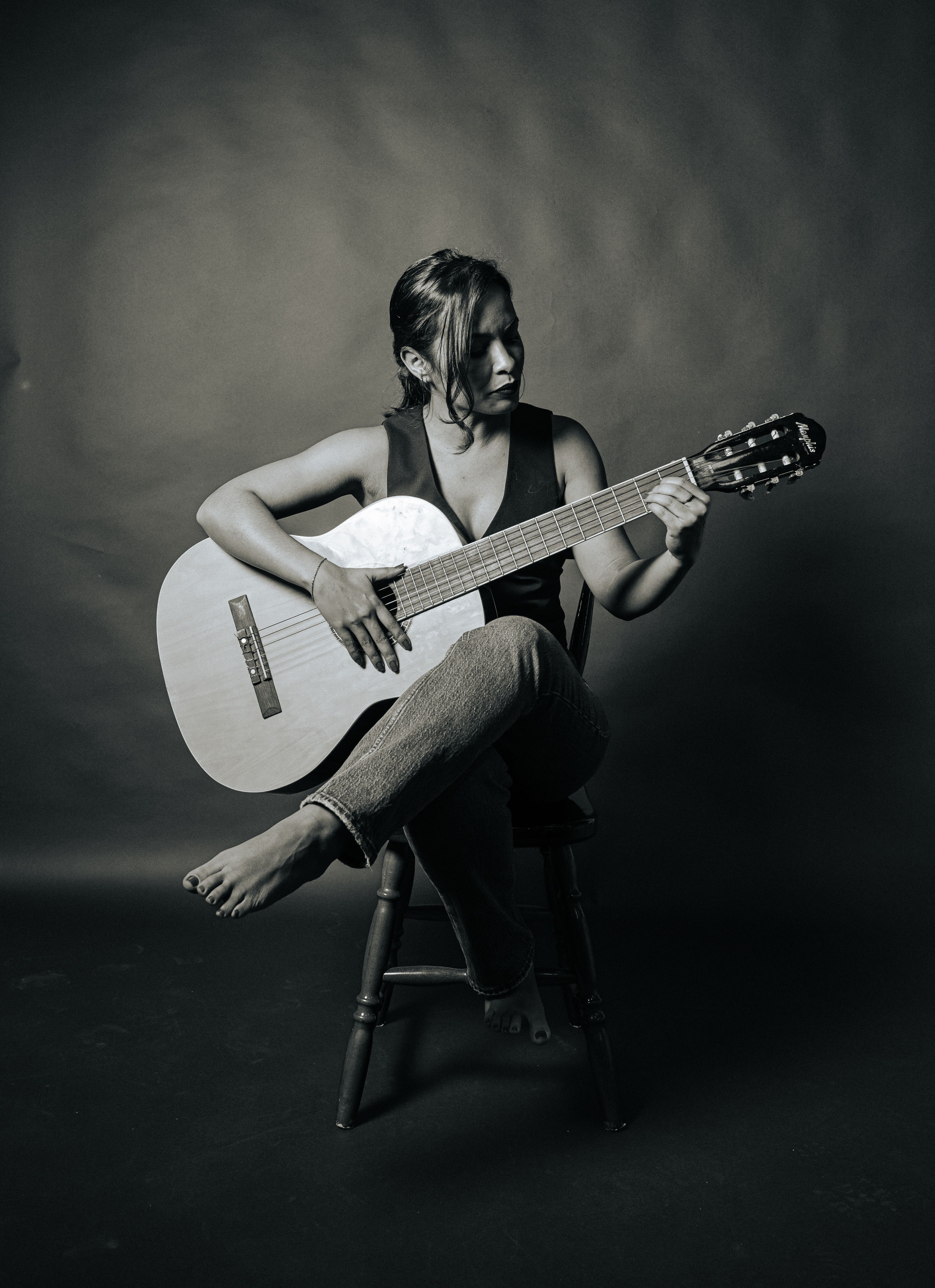 Artistic black and white portrait of a guitarist in a studio setting.