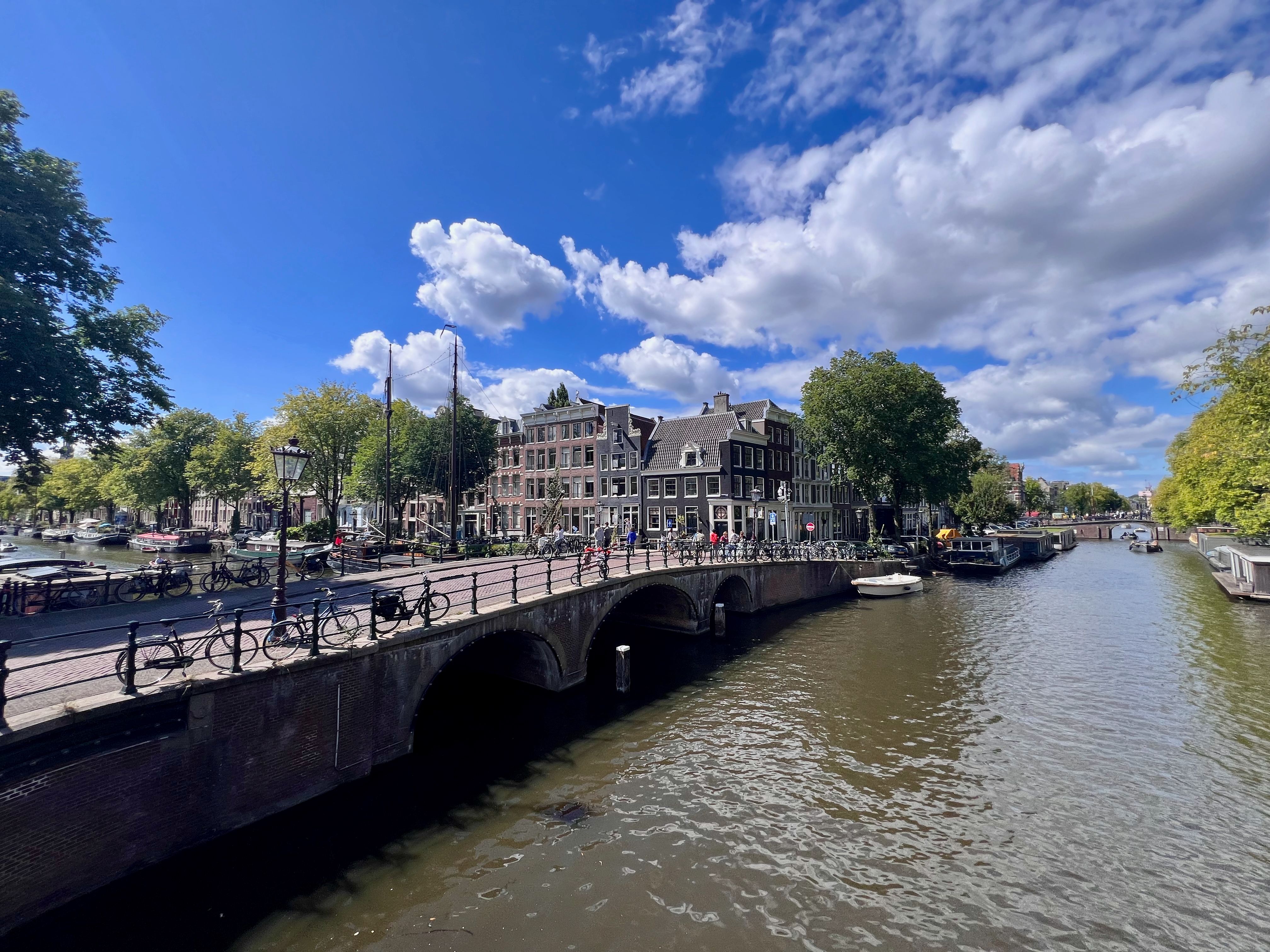 Picturesque view of Amsterdam's iconic canals and historic architecture under a bright blue sky. — photo by Philippe WEICKMANN / Pexels
