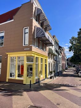 Bright sunny street scene in Amsterdam featuring colorful facades and striped awnings.