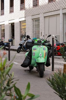 A green vintage scooter parked on a charming Paris street, evoking retro vibes and urban lifestyle.
