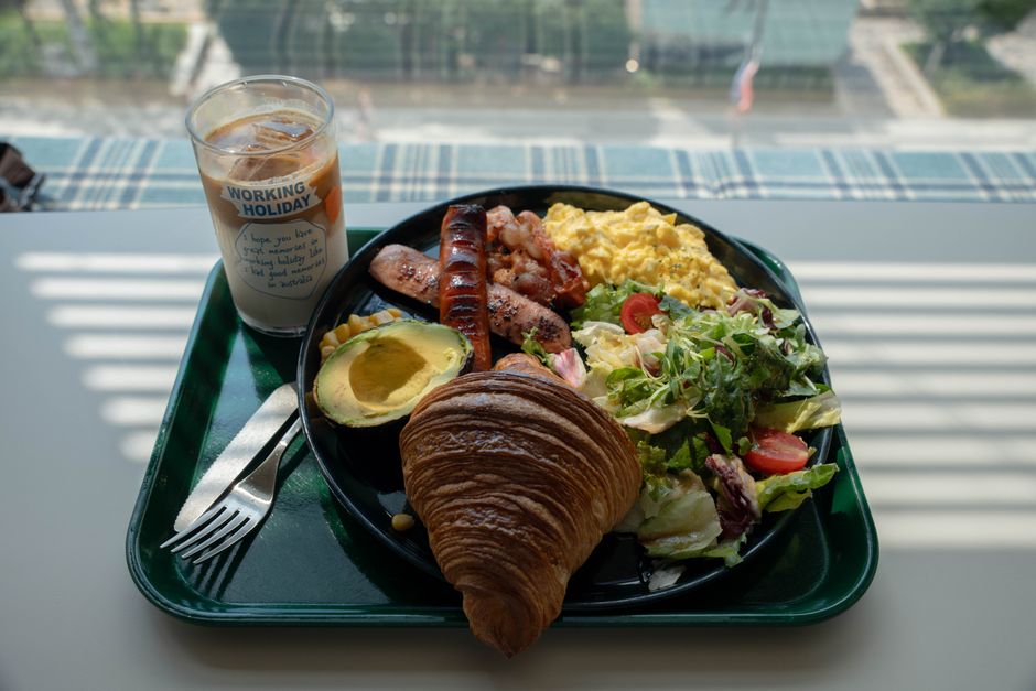 Enjoy a hearty breakfast with scrambled eggs, sausages, salad, and iced coffee in South Korea.