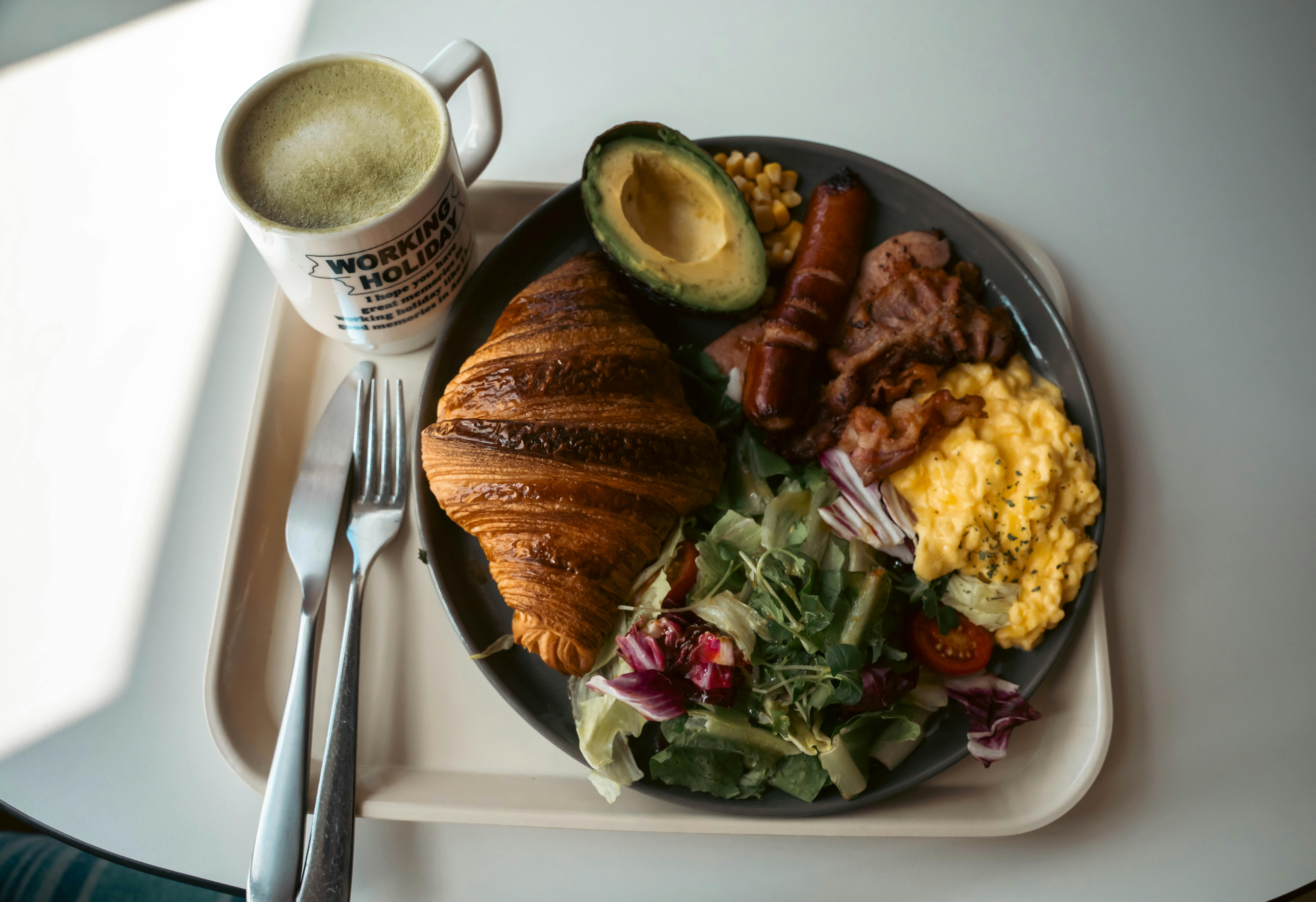 Delicious breakfast plate with croissant, scrambled eggs, and coffee in a cozy setting.