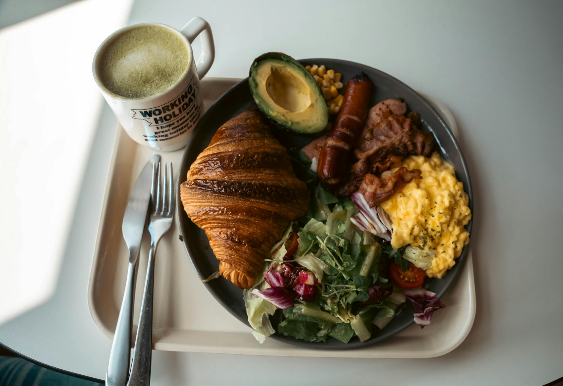 Delicious breakfast plate with croissant, scrambled eggs, and coffee in a cozy setting.