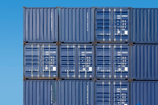 Close-up of blue shipping containers stacked high at Rotterdam Port under a clear blue sky.