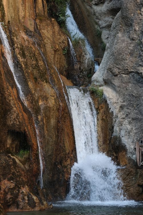 Free Spectacular waterfall cascading over rugged rocks amidst lush greenery. Stock Photo