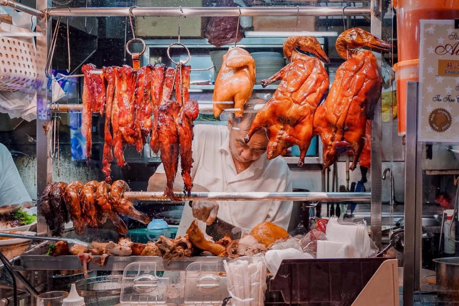 Vibrant market stall with assorted roasted meats, showcasing culinary street food delicacies.