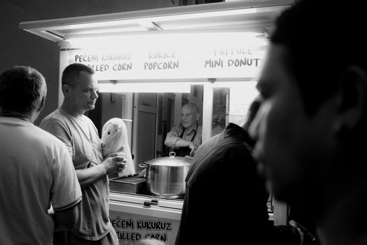Black and white photo capturing a busy street food stall in Croatia, serving grilled corn and popcorn.