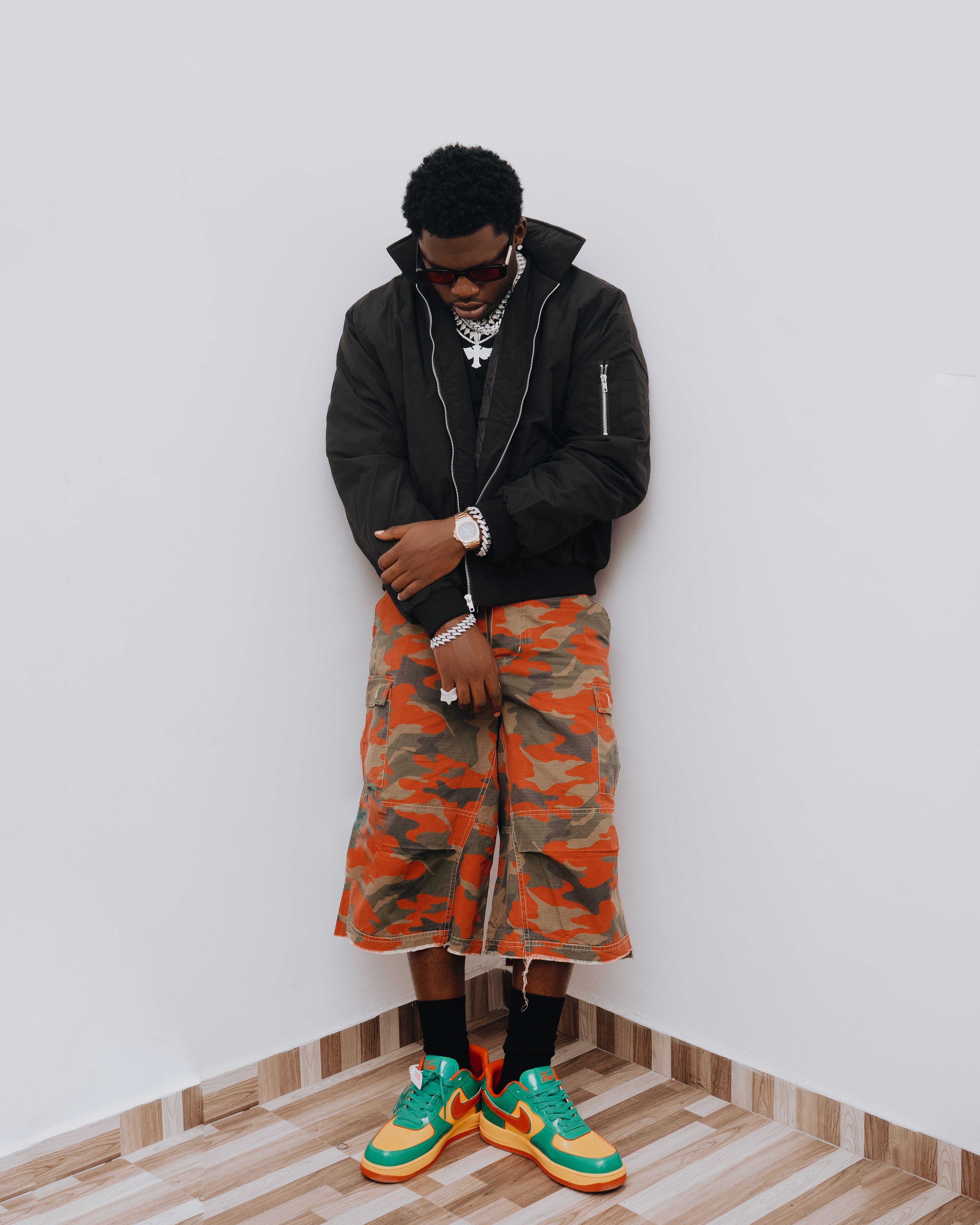 Fashionable man wearing camouflage pants and colorful sneakers indoors.