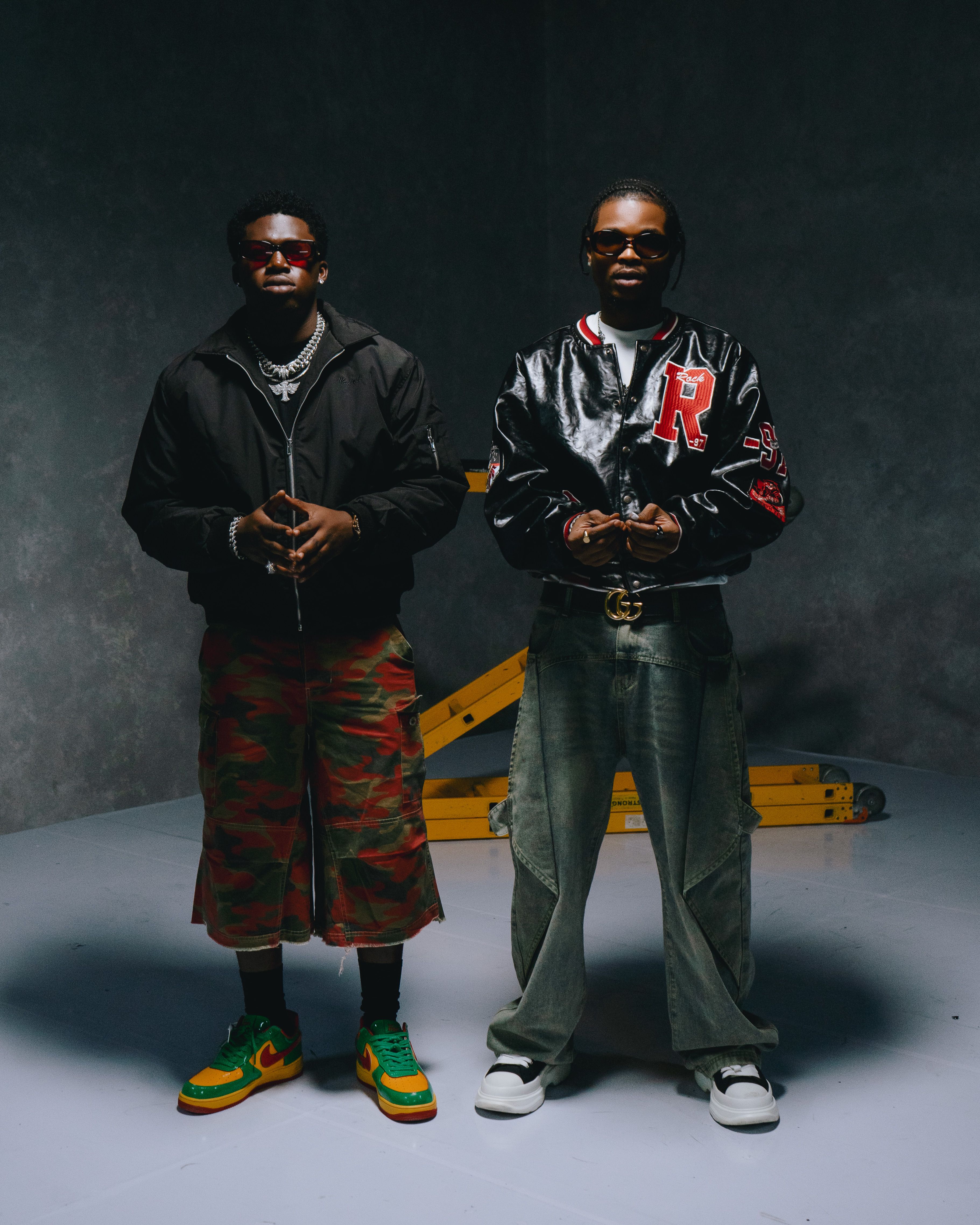 Two fashionable men in modern streetwear posing confidently indoors.
