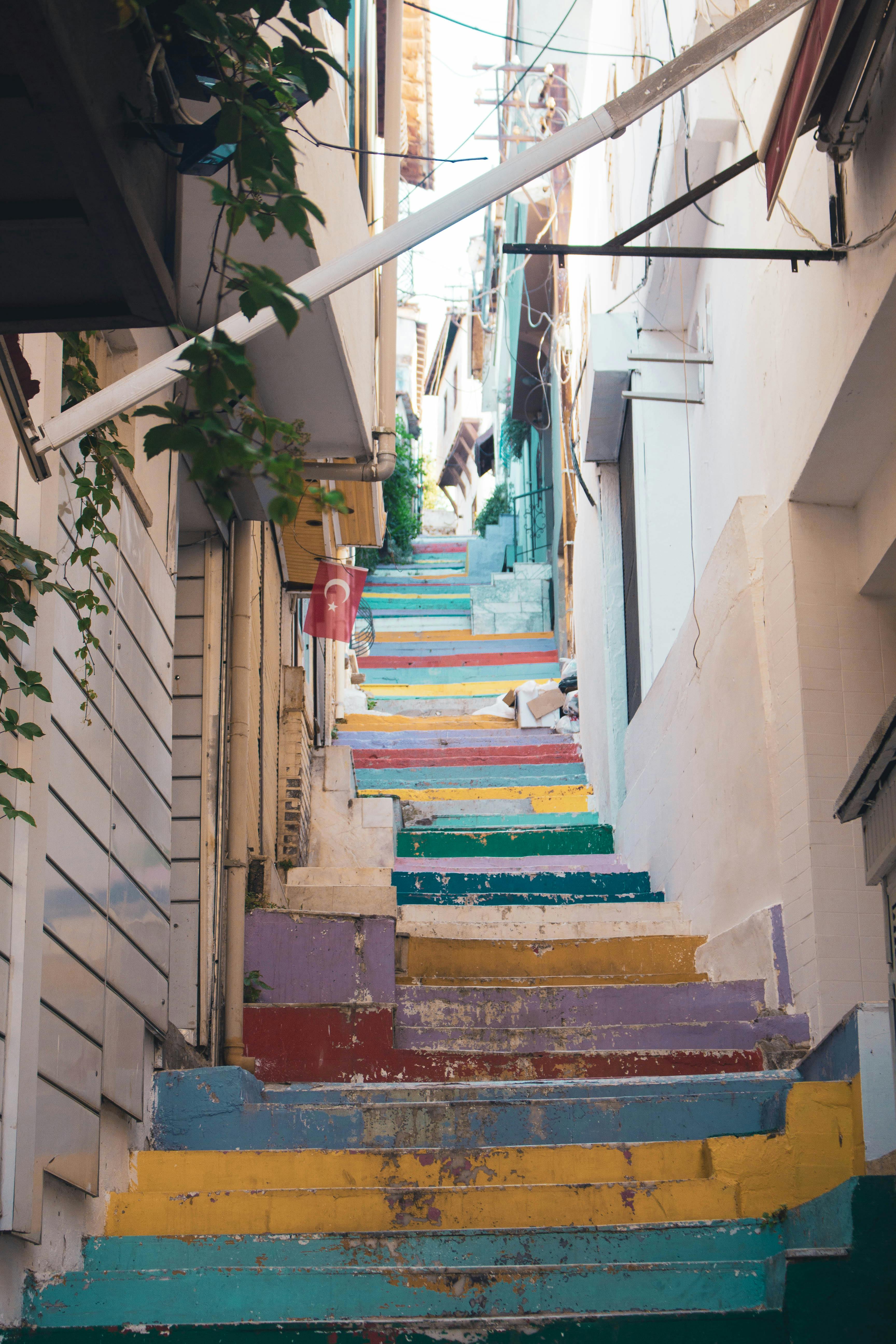 Vibrant rainbow stairs in an alley in Kuşadası, Türkiye, showing artistic urban design.