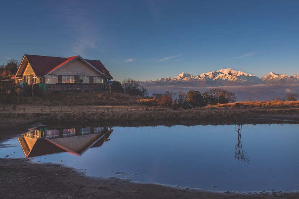 A red roofed trekkers' lodge by a pond on the Singalila ridge, Kanchenjunga glowing on the skyline