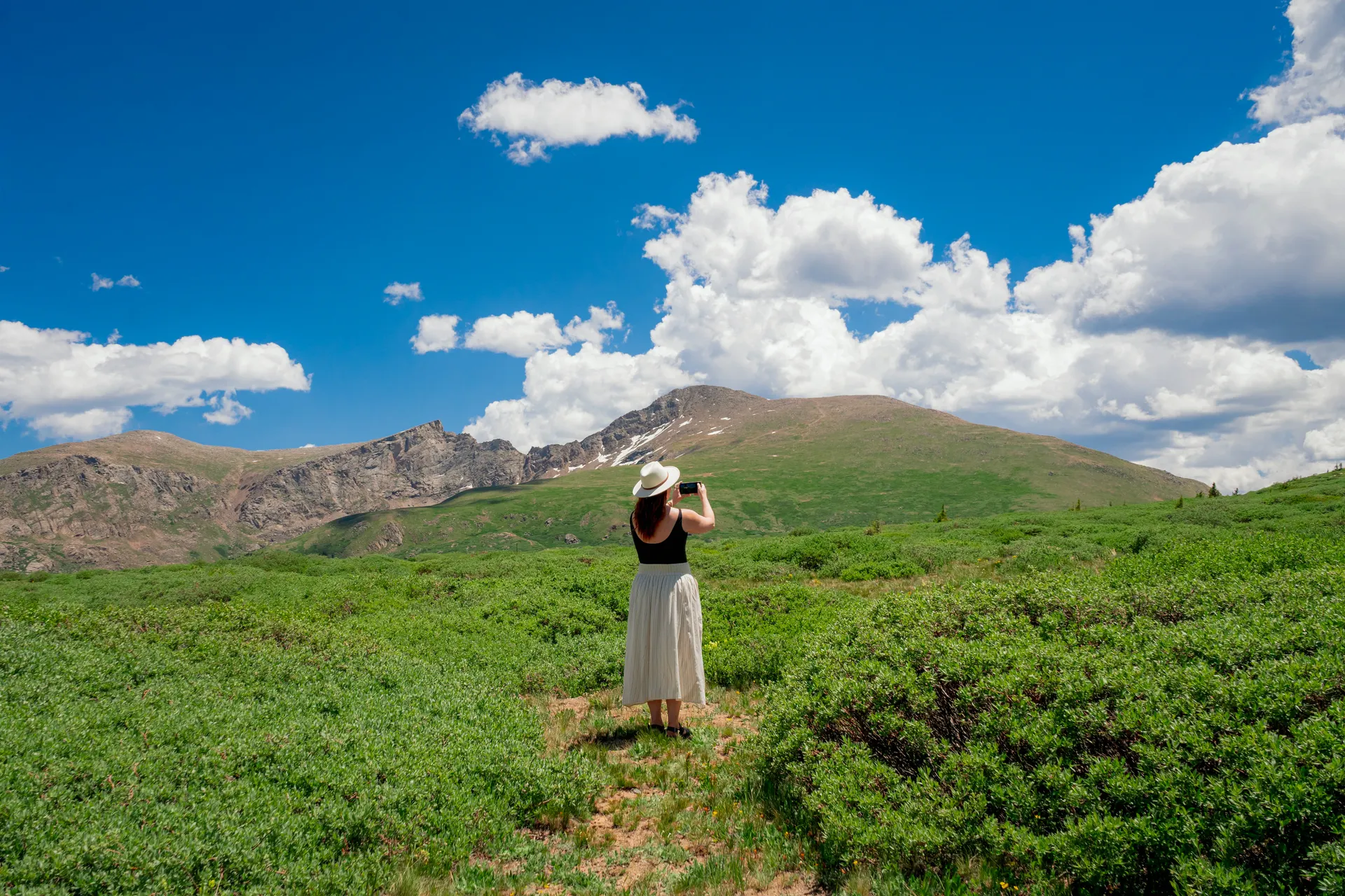 Woman photographing a mountain view in the Colorado Rockies in summer Woman photographing a mountain view in the Colorado Rockies in summer