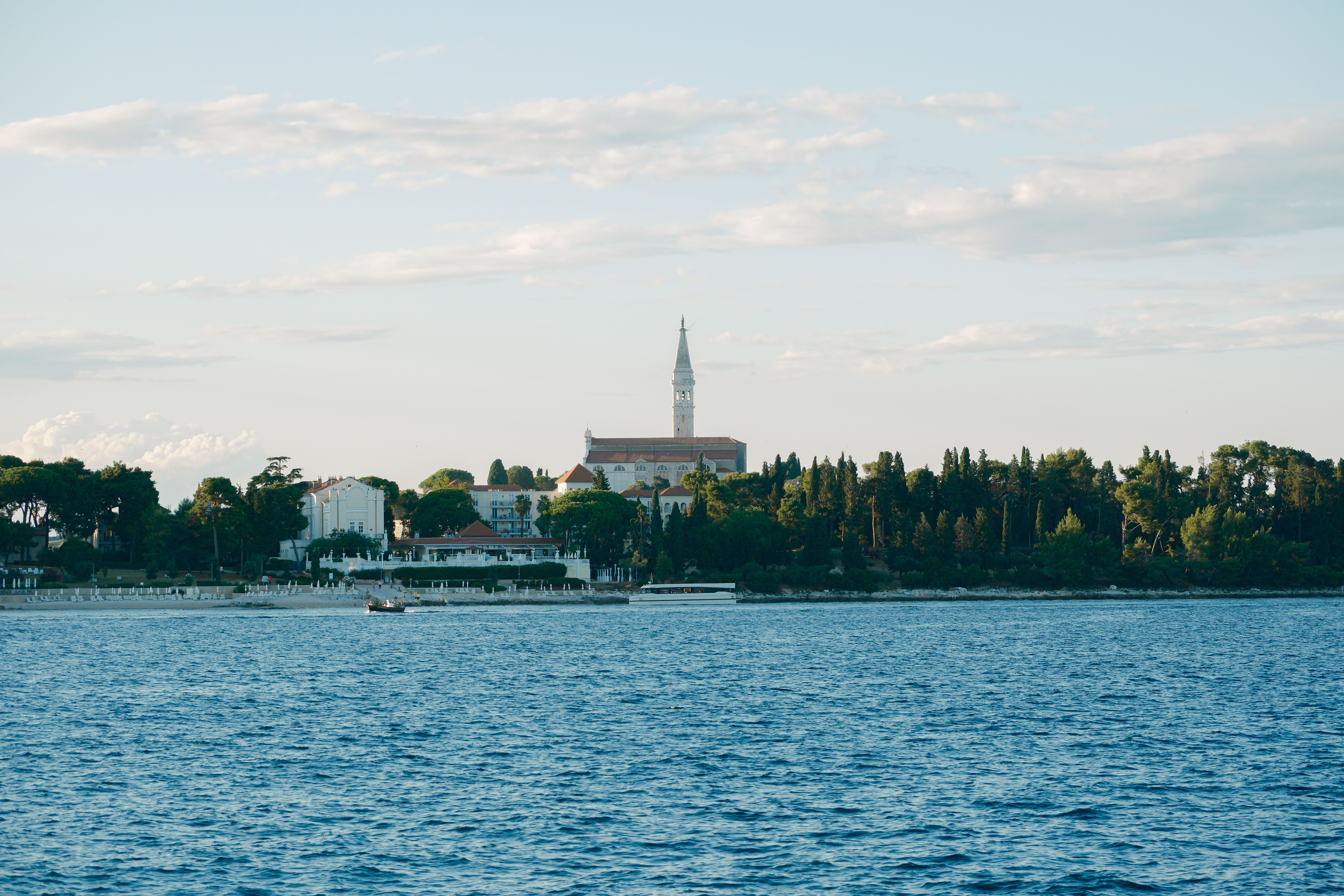 Discover the serene beauty of a Croatian seaside town with lush greenery and iconic architecture.