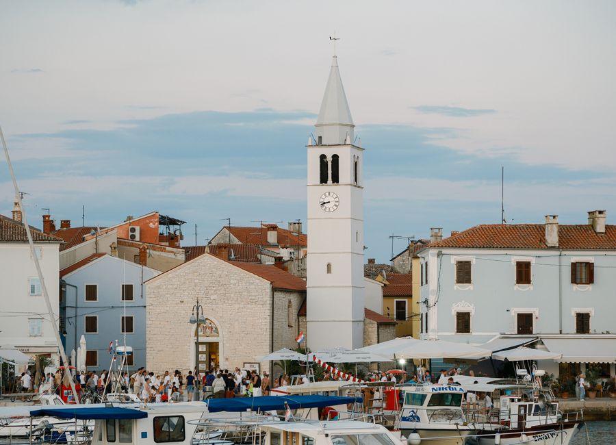 Picturesque Croatian harbor with clock tower and boats at dusk.
